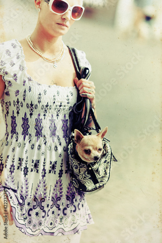 Foto: Frau mit Hund in der Handtasche im Retrostil Frau mit Hund in der Handtasche im Retrostil