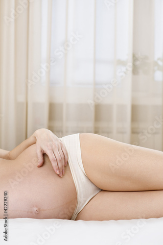 Photo: Pregnant woman lying on bed Pregnant woman lying on bed