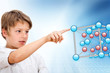 Young boy pointing at 3D molecules.