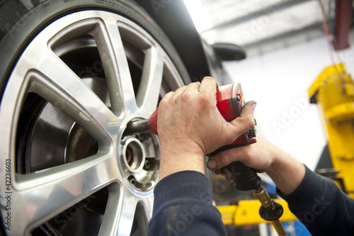 Photo: Detail car mechanic changing tyre Detail car mechanic changing tyre