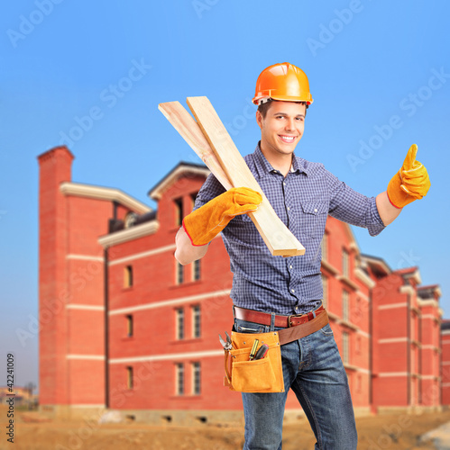 Foto: A smiling carpenter holding sills and giving thumb up A smiling carpenter holding sills and giving thumb up