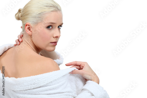 Foto: Woman putting her bathrobe on after a bath Woman putting her bathrobe on after a bath