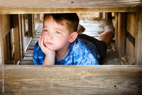 Foto: Unhappy child hiding and sulking while playing on playground Unhappy child hiding and sulking while playing on playground