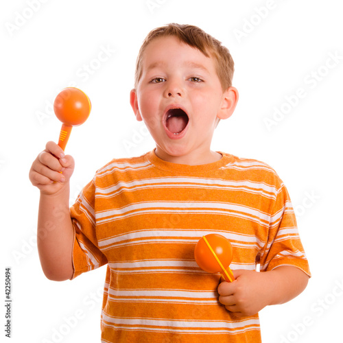 Photo: Happy child playing maracas and signing isolated on white Happy child playing maracas and signing isolated on white