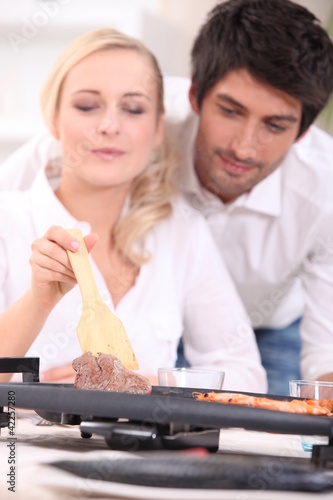 Foto: Couple cooking surf and turf on a tabletop hotplate Couple cooking surf and turf on a tabletop hotplate