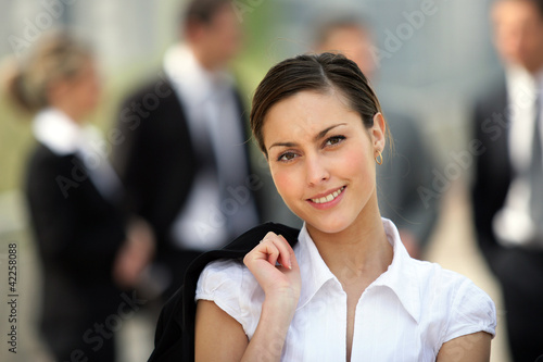 Photo: Businesswoman stood in front of colleagues outside Businesswoman stood in front of colleagues outside