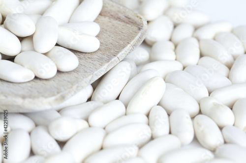 Photo: White beans on wooden spoon and a white background White beans on wooden spoon and a white background
