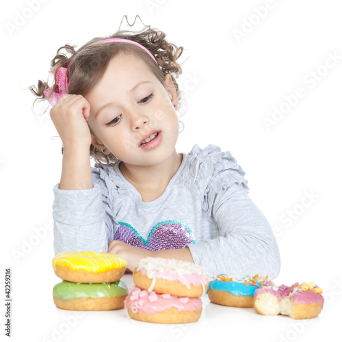 Photo: Little beautiful girl with donuts over white Little beautiful girl with donuts over white