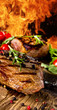 Grilled beef steaks with flames on background