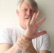 senior man winces at the pain in his hand