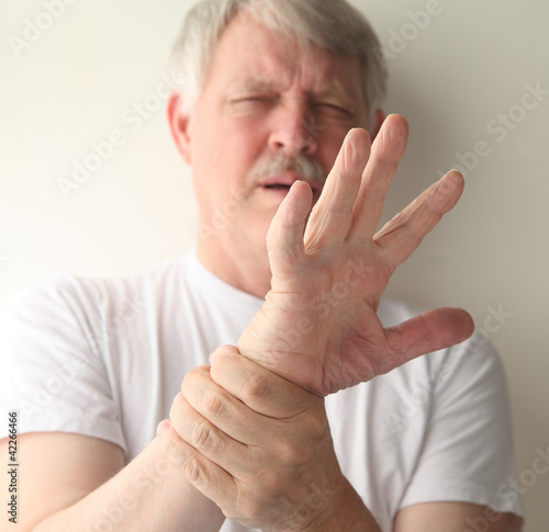 Photo: senior man winces at the pain in his hand senior man winces at the pain in his hand