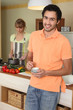 woman stirring into saucepan and man holding cup of coffee