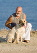 Middle-aged man with Labrador female dog on the sea coast