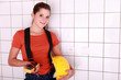 handywoman posing with an ammeter and a helmet