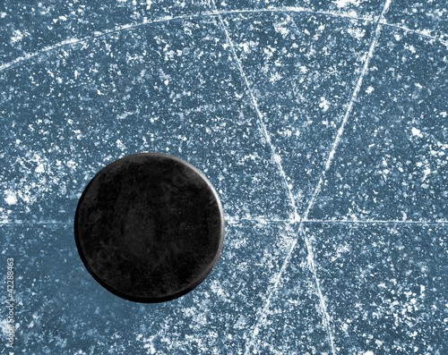 Photo: black hockey puck on ice rink black hockey puck on ice rink