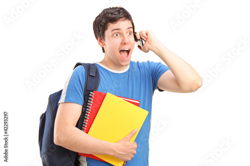 Foto: A surprised student talking on a phone and holding notebooks A surprised student talking on a phone and holding notebooks