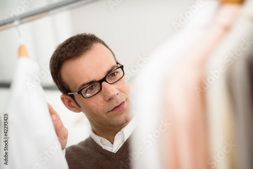 Photo: adult man choosing shirt in clothes shop adult man choosing shirt in clothes shop