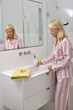 Seniorin trinkt im Badezimmer ein Glas Wasser