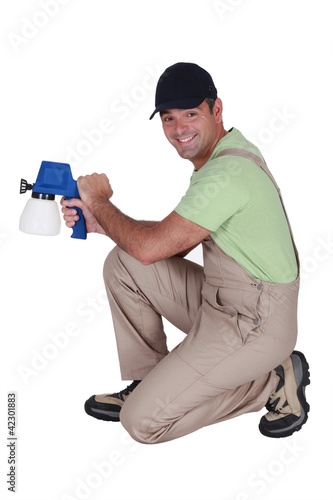 Foto: Man kneeling with paint sprayer Man kneeling with paint sprayer