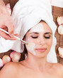 Beautiful young woman getting facial mask