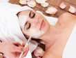 Beautiful young woman getting facial mask