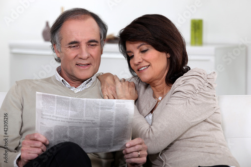 Photo: Couple reading the newspaper together Couple reading the newspaper together