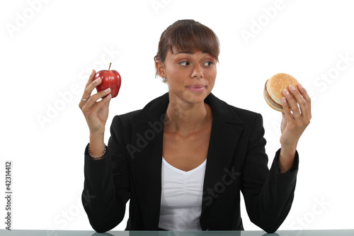 Foto: Woman choosing between burger and apple Woman choosing between burger and apple