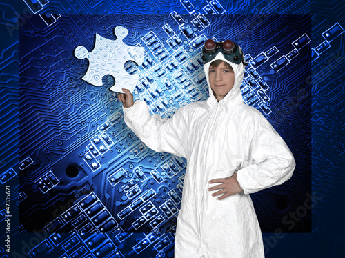 Photo: Young man holding a piece of puzzle against a electronic blue bo Young man holding a piece of puzzle against a electronic blue bo