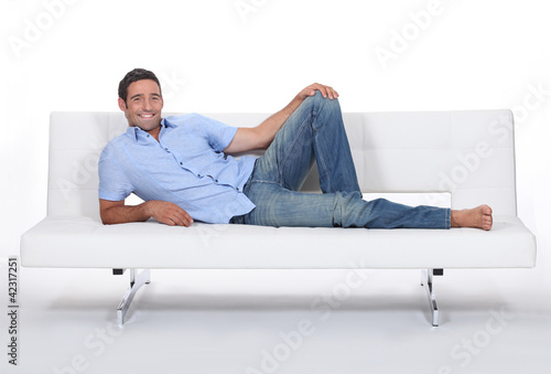 Photo: Barefoot man lying on a couch Barefoot man lying on a couch