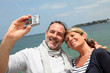 Retired couple taking picture of themselves by the sea