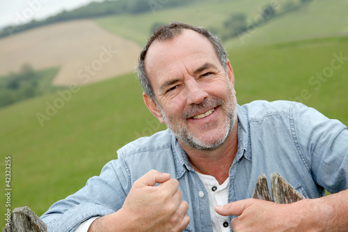 Foto : Portrait of smiling farmer leaning on fence Portrait of smiling farmer leaning on fence