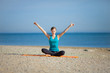 Young woman meditating on the beach