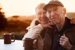 Cute senior couple in jackets outside at table smiling