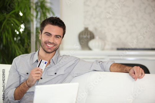 Photo: Man using credit card online Man using credit card online