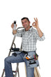 Carpenter with mobile giving the OK