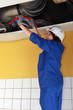 Plumber running pipes across a ceiling