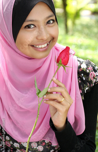 Portrait of beautiful young muslim girl holding a red rose