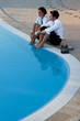 Photo: Young couple relaxing by pool Young couple relaxing by pool