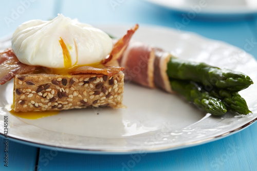 Photo: Poached egg and bacon on whole wheat toast with green asparagus Poached egg and bacon on whole wheat toast with green asparagus