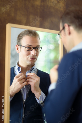Photo: Young man dressing up and looking at mirror Young man dressing up and looking at mirror