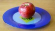 Red apple rotates on a plate.