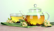 teapot and cup with linden tea and flowers