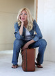 Foto: Young woman sitting on a suitcase Young woman sitting on a suitcase