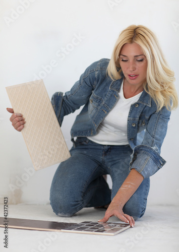 Photo: Young woman choose tiles Young woman choose tiles