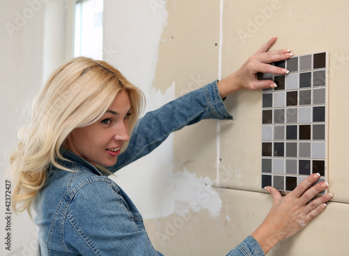 Photo: Young woman choose tiles Young woman choose tiles