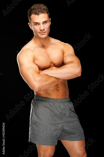 Photo: Portrait of handsome young man standing on black Portrait of handsome young man standing on black