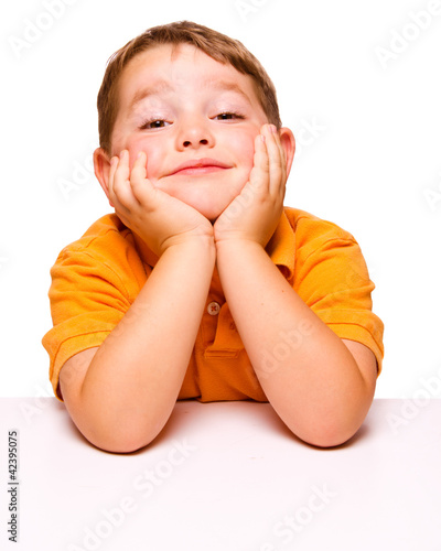 Photo: Mischievous bored child sitting at desk Mischievous bored child sitting at desk