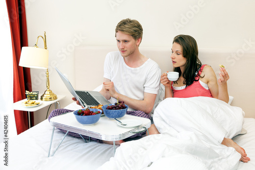 Foto: Paar mit Laptop frühstückt im Bett Paar mit Laptop frühstückt im Bett