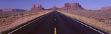 Photo: This is Route 163 that runs through the Navajo Indian Reservation. The road runs large through the middle and gets smaller as it heads toward the rocks. The red rocks of Monument Valley are in the background. The scrub plants of the desert are on either side of the road. This is Route 163 that runs through the Navajo Indian Reservation. The road runs large through the middle and gets smaller as it heads toward the rocks. The red rocks of Monument Valley are in the background. The scrub plants of the desert are on either side of the road.