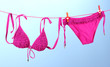 Women's swimsuit hanging on a rope on blue background